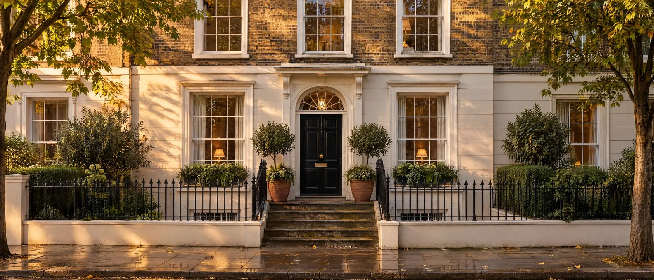 A stucco fronted period terrace in north west London in late afternoon light, with steps up to a black front door