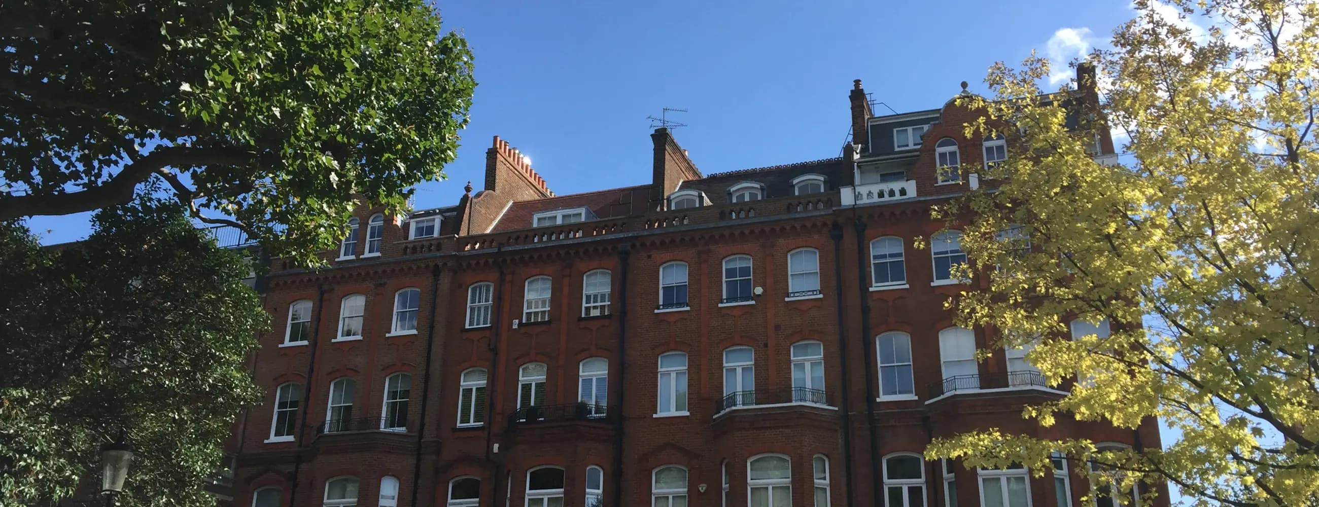 A late Victorian red brick mansion block with bay windows, balconies, dormers and tall chimneys